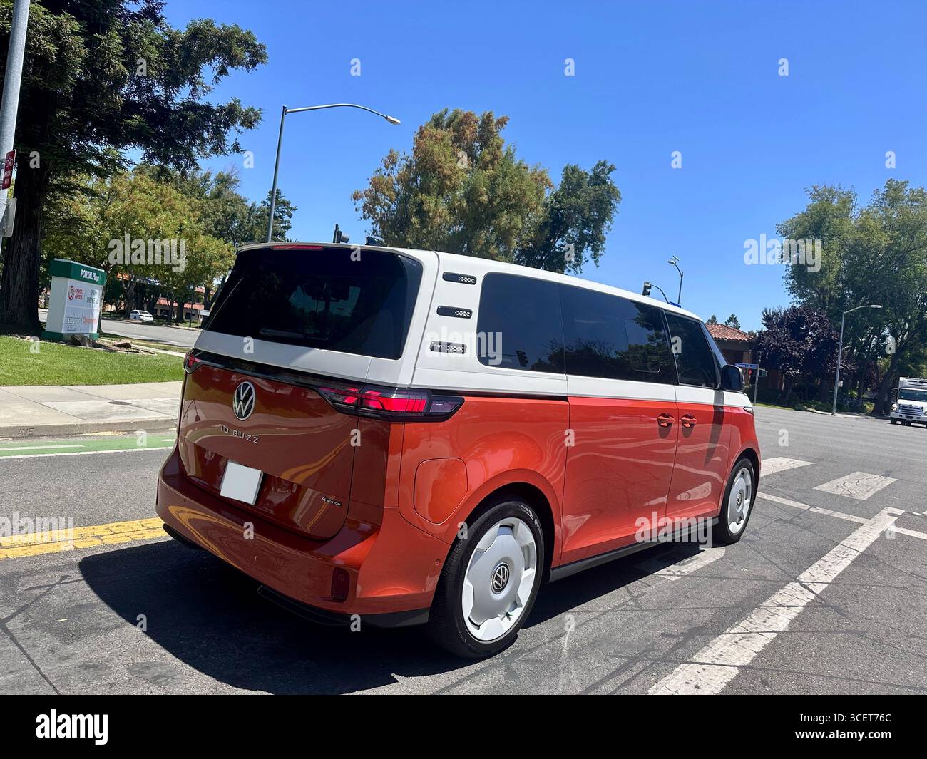 Ein rot-weißer Volkswagen-Ausweis. Der elektrische Van fährt an einem sonnigen Tag in Kalifornien, USA. Der im Retro-Stil inspirierte EV-Kleinbus kombiniert moderne Elemente - Smartphone-aufgenommenes Stockfoto