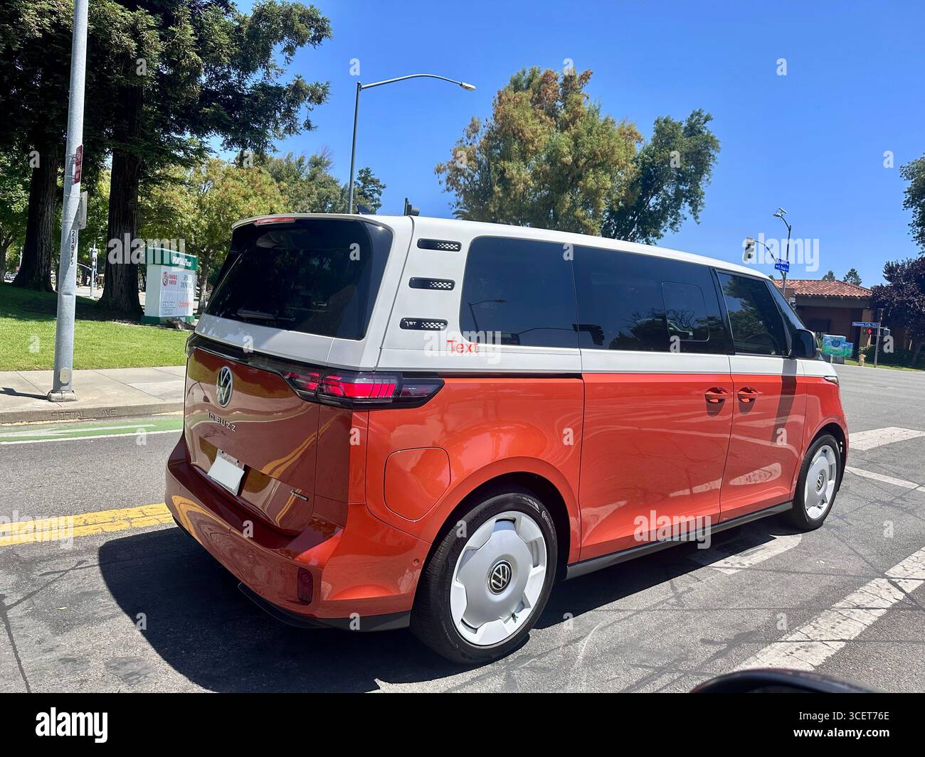 Ein rot-weißer Volkswagen-Ausweis. Der elektrische Van fährt an einem sonnigen Tag in Kalifornien, USA. Der im Retro-Stil inspirierte EV-Kleinbus kombiniert moderne Elemente - Smartphone-aufgenommenes Stockfoto