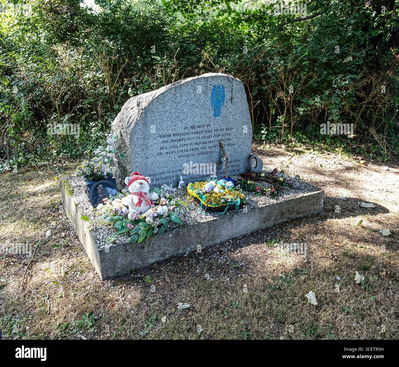 Gedenkstein für Babys im St. Columcille's Hospital, Loughlinstown, Dublin, Irland, mit Blumen, Spielzeug und Tribut, die in Erinnerung bleiben. Stockfoto