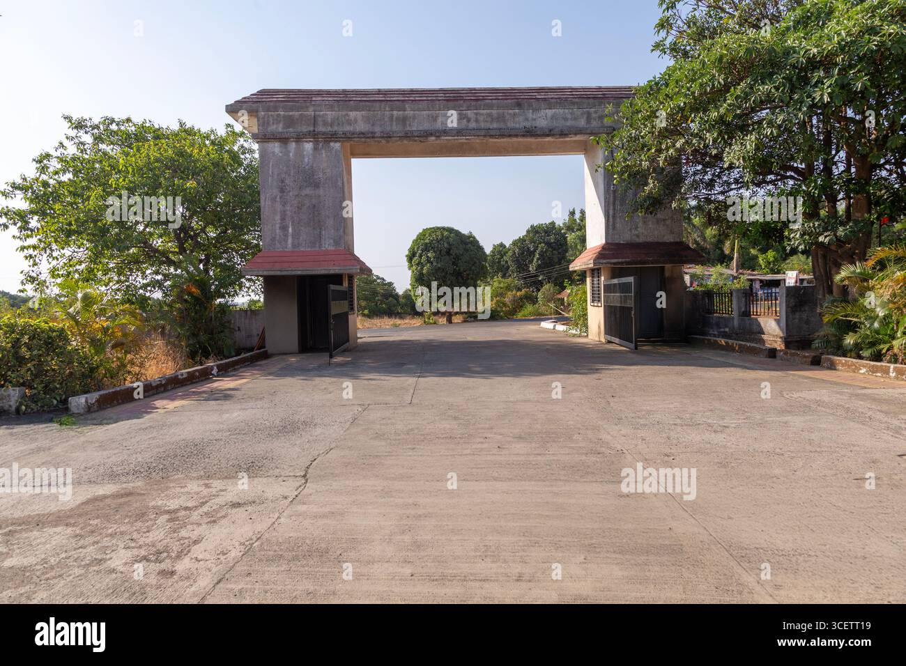 Zufahrt zu einem modernen Gebäude mit geparkten Autos und einem Bus, mit landschaftlich gestaltetem Grün und klarem Himmel. Stockfoto