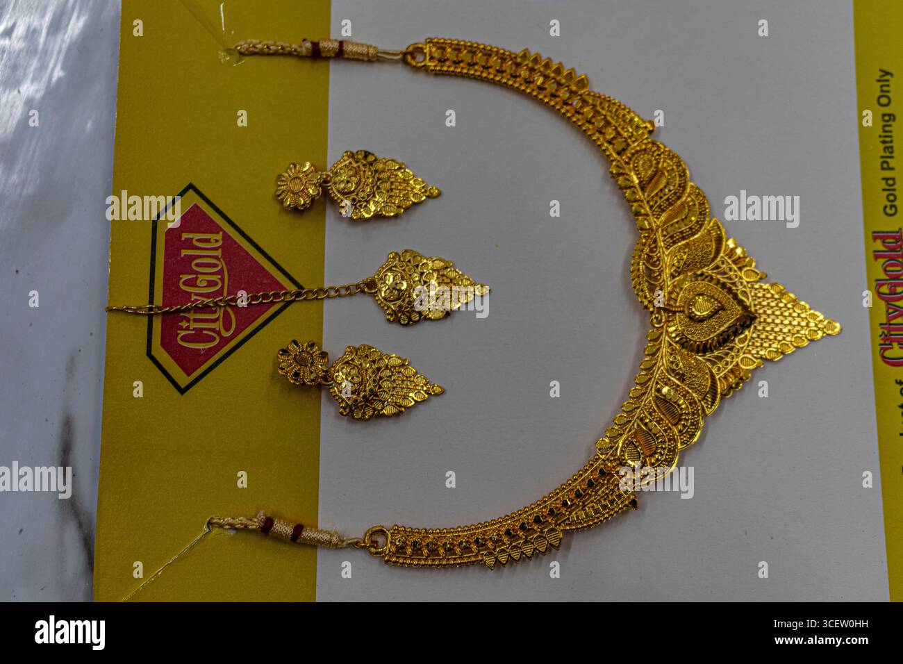 Wunderschöne vergoldete Halskette mit Ohrringen auf weißem Brett in heller Beleuchtung Stockfoto
