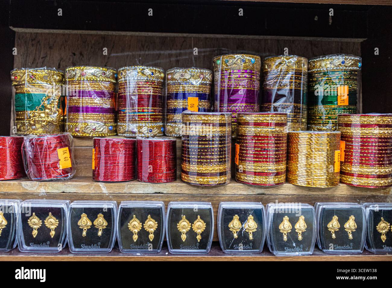 Traditionelle festliche Armreifen in Kunststoffverpackung, die neben goldenen Ohrringen für Kunden gestapelt sind Stockfoto