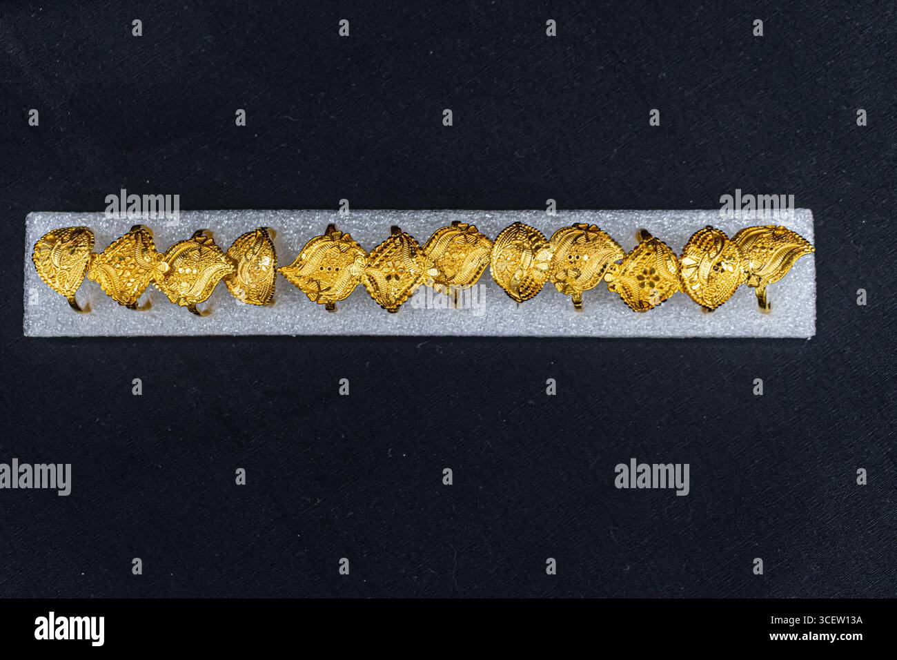 Traditionelle handgefertigte goldene Ringe mit geprägten Mustern auf schwarzem Hintergrund Stockfoto