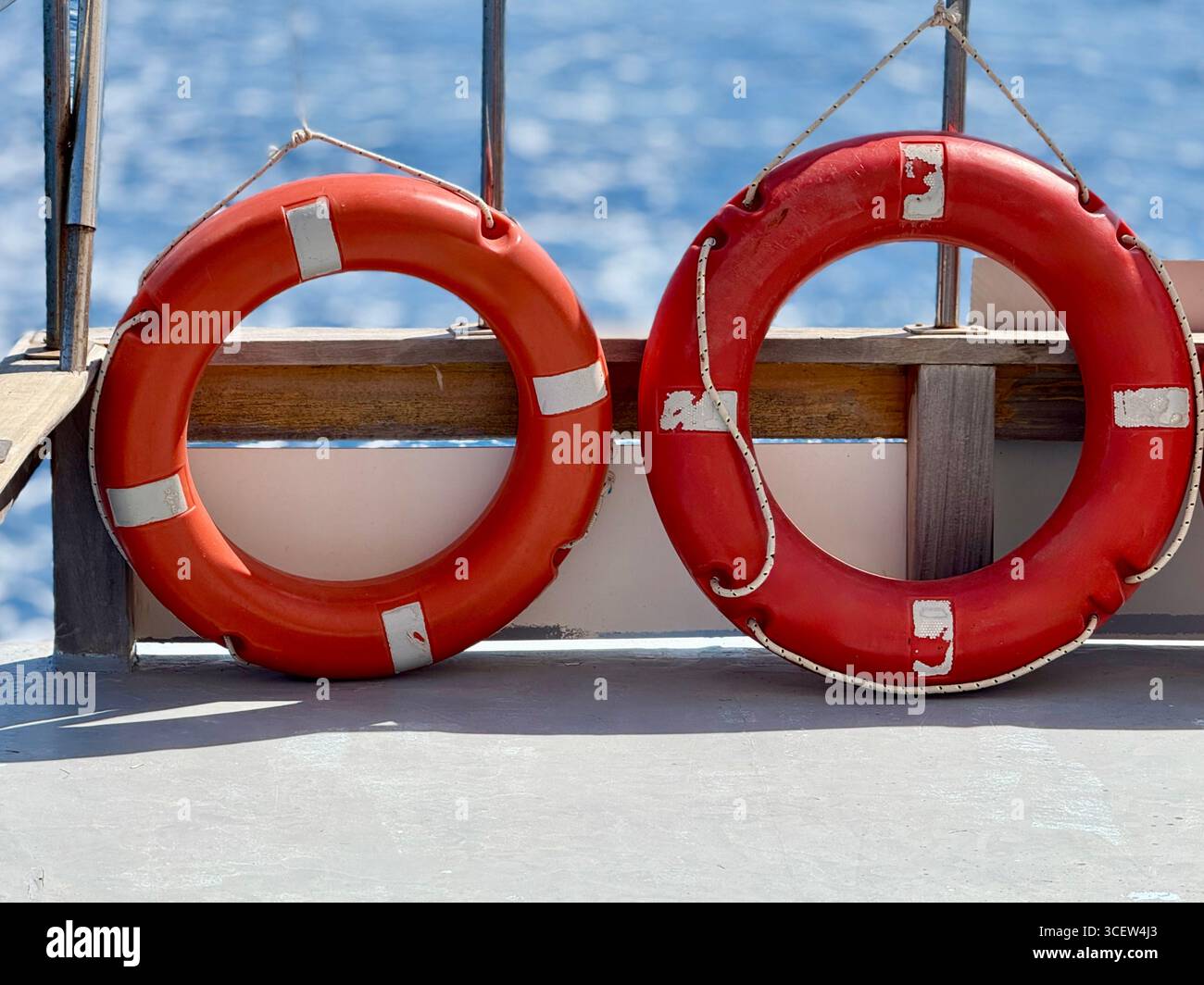 Zwei helle Rettungsschalen hängen an der Seite eines Touristenbootes mit dem blauen Meer im Hintergrund, die Sicherheit und Reisen symbolisieren Stockfoto