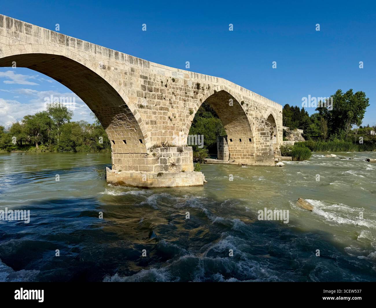 Türkei, Antalya, Aspendos. Die alte Brücke in der Türkei, erhalten in einer malerischen ländlichen Landschaft unter einem klaren blauen Himmel. Aspendos. Alte Steinbrücke - Smartphone-aufgenommenes Stockfoto