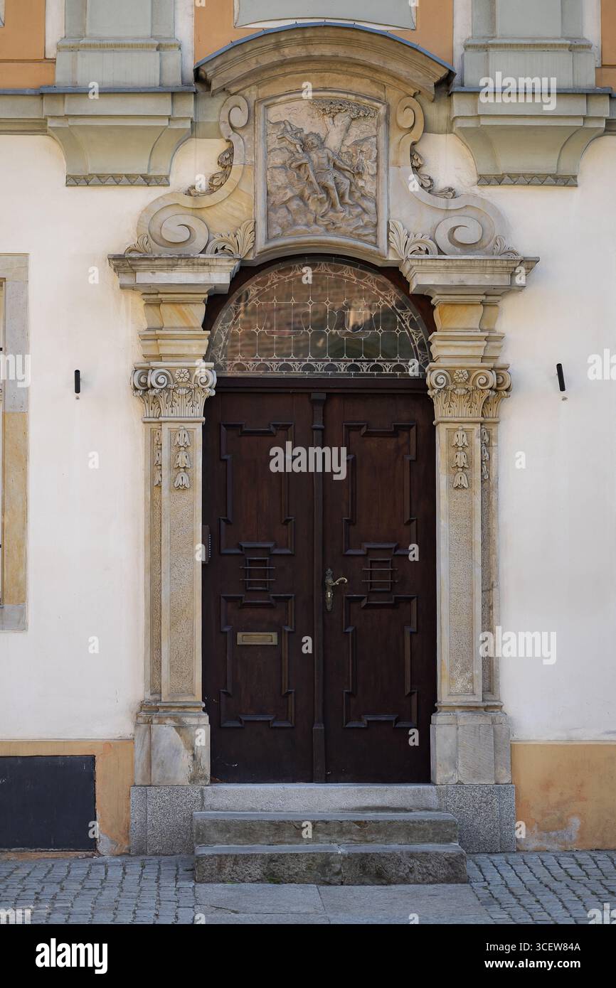 Kunstvoll geschnitzte Holztür mit kunstvoll verziertem Steinbogen und detailliertem Basreliefs, die elegante Handwerkskunst der historischen Architektur zeigt Stockfoto