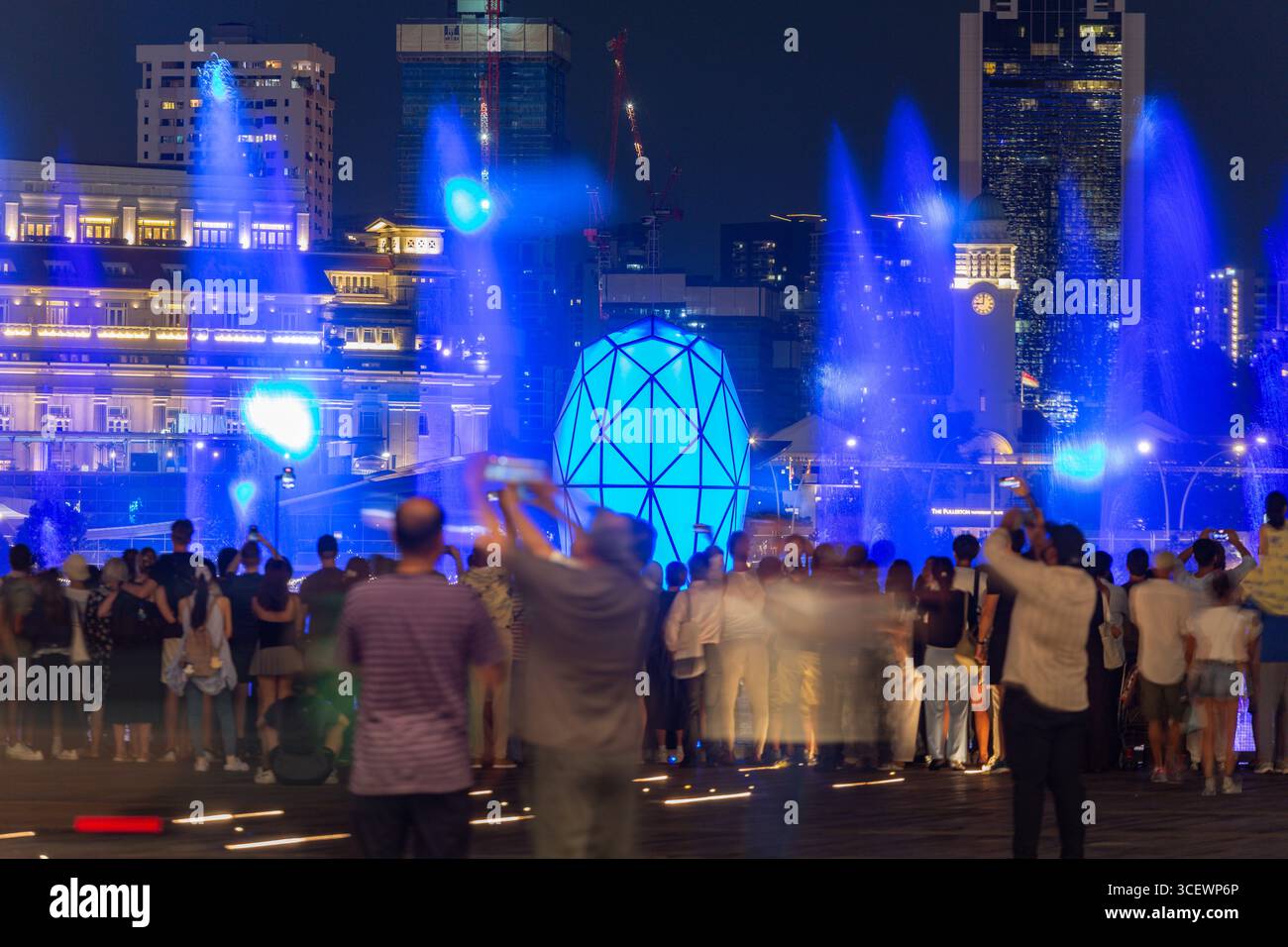 Touristen benutzen ihre Telefone, um Spectra Licht- und Soundshow zu filmen, wunderschöne Wasserfontänen in Marina Bay Sands, Singapur. Stockfoto