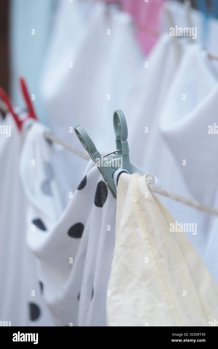 Kleidung hängt an einer Schlange in einer sonnigen Umgebung im Freien Stockfoto