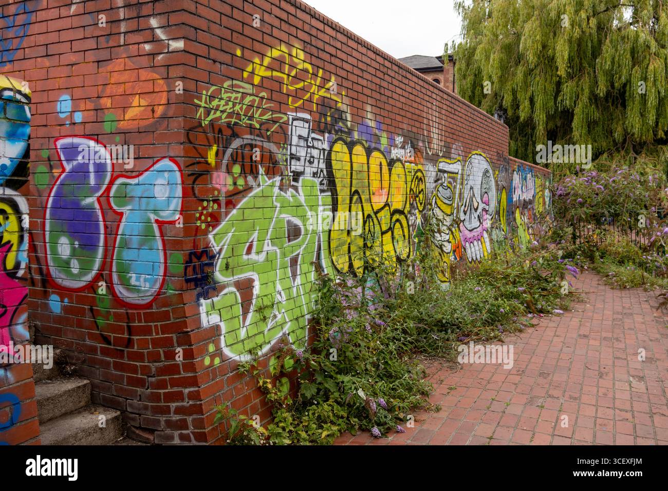Street Art Graffiti auf einer roten Ziegelwand mit kräftigen Farben, Tags und Sprühfarbe in einer städtischen Umgebung Stockfoto