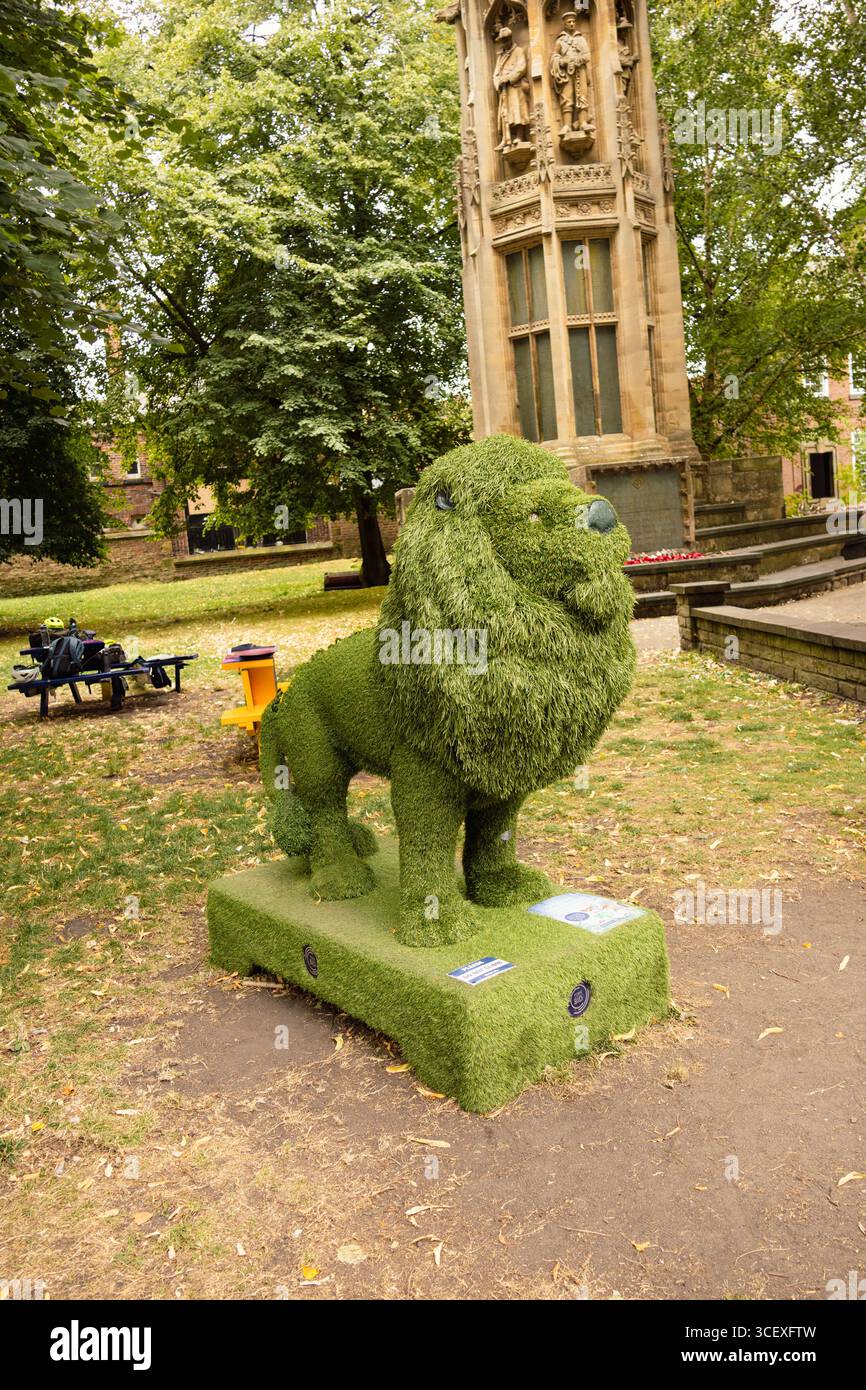 Eine kreative Löwenskulptur aus getrimmtem Grün, die in einem öffentlichen Park ausgestellt wird und Stärke und Kunst in der Landschaftsgestaltung symbolisiert Stockfoto