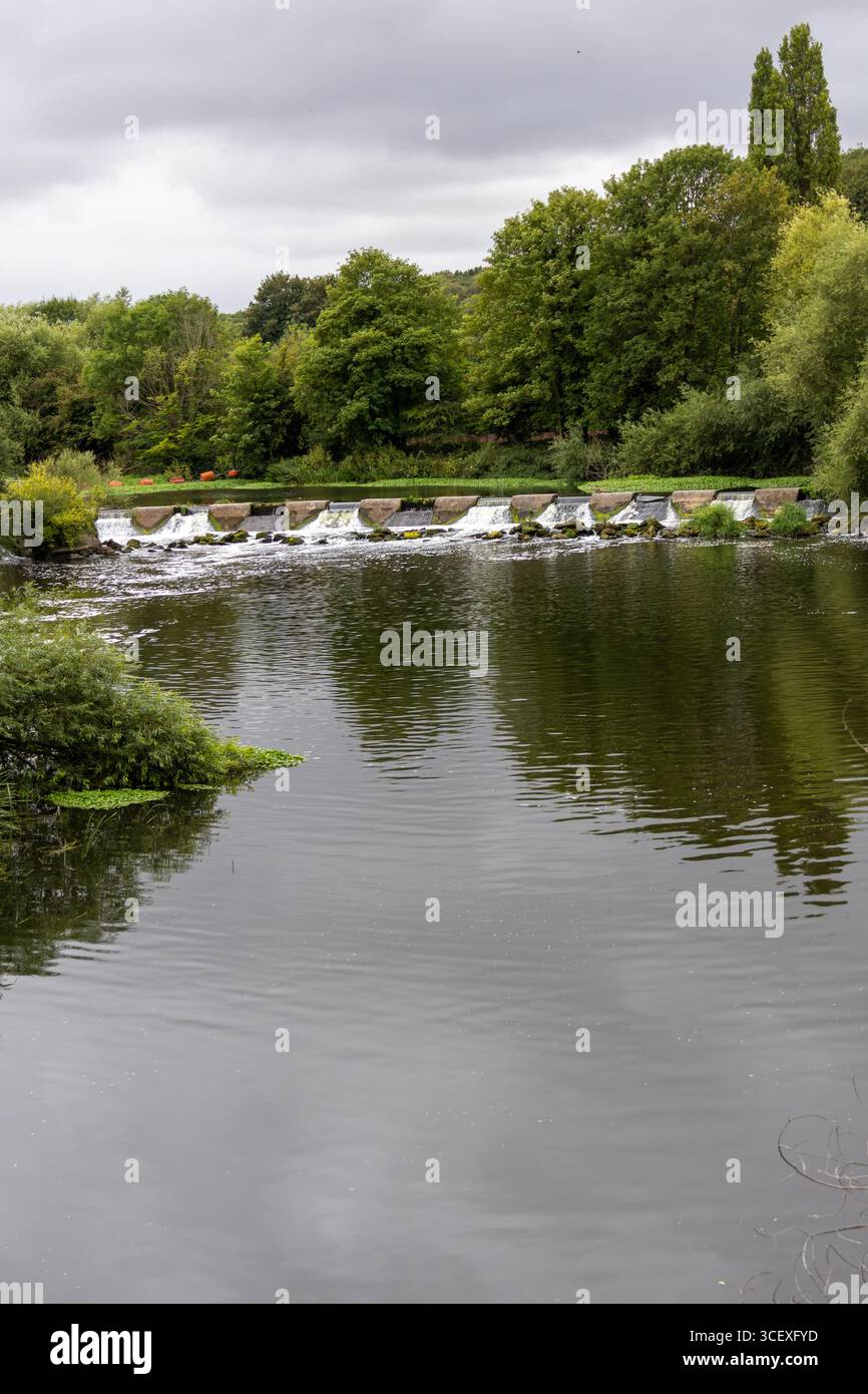 Weite Aussicht auf ein Flussweh mit kaskadendem Wasser, Felsen und üppiger grüner Vegetation rund um die Flüsse Stockfoto