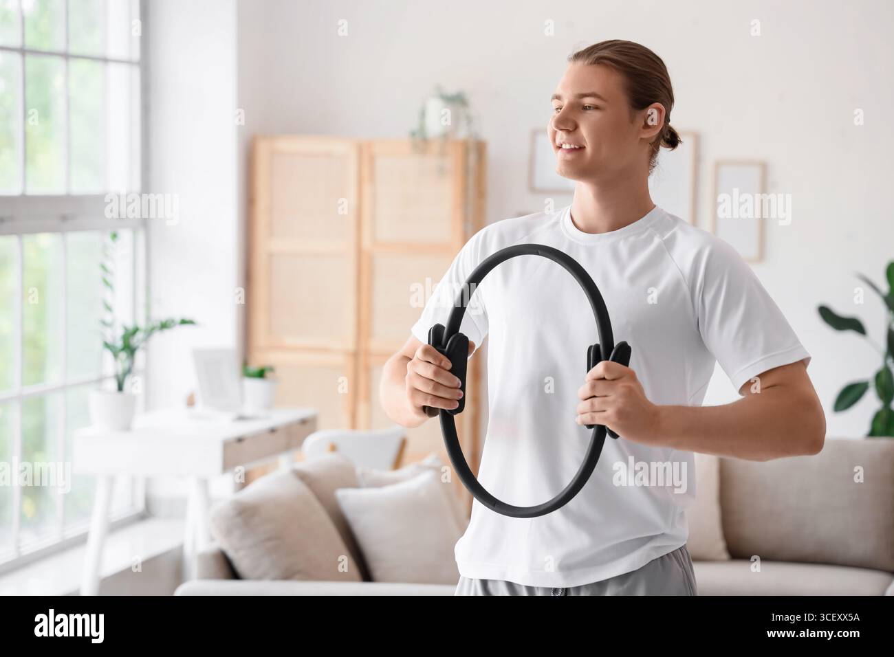 Sportlicher junger Mann mit Pilates-Ring zu Hause Stockfoto