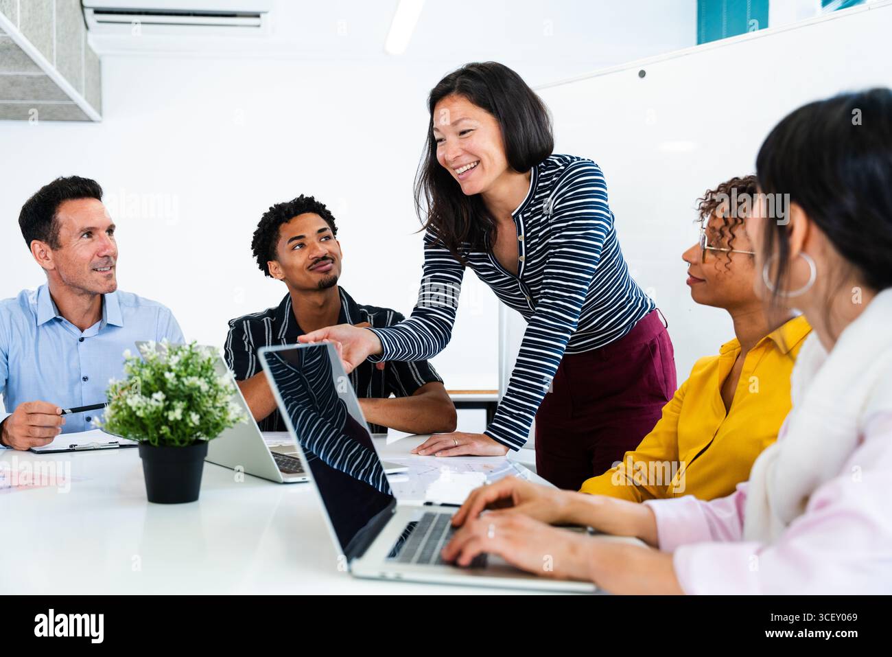Verschiedene Kollegen nehmen aktiv an einem produktiven Büromeeting Teil, nutzen Laptops und tauschen Ideen aus, um gemeinsame Ziele zu erreichen, und fördern so eine Coll Stockfoto