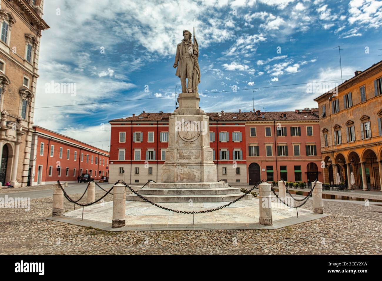 Modena, italien 20. august 2025: Steinstatue des italienischen Patrioten ciro menotti mit einer Flagge auf der piazza grande, modena, italien, unter bewölktem Himmel Stockfoto