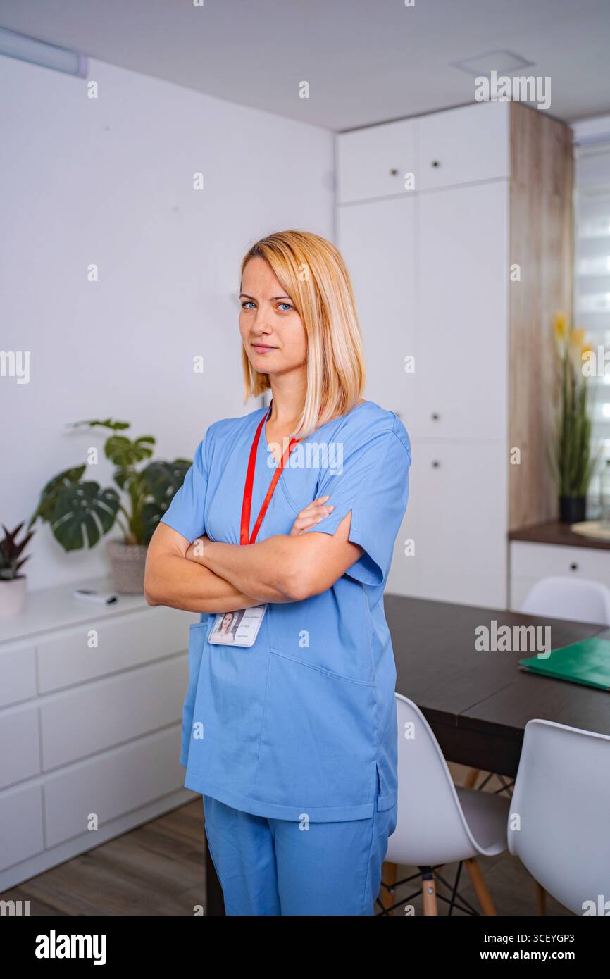 Selbstbewusste Ärztin posiert mit überkreuzten Armen in der Arztpraxis Stockfoto