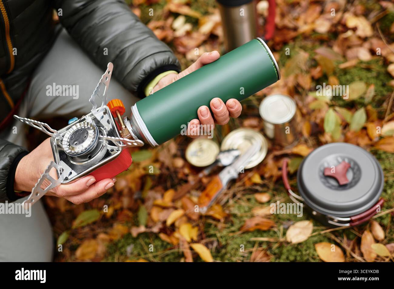 Eine Seniorin bereitet einen Lagerofen zum Kochen vor, während sie eine friedliche Wanderung im Wald genießt Stockfoto