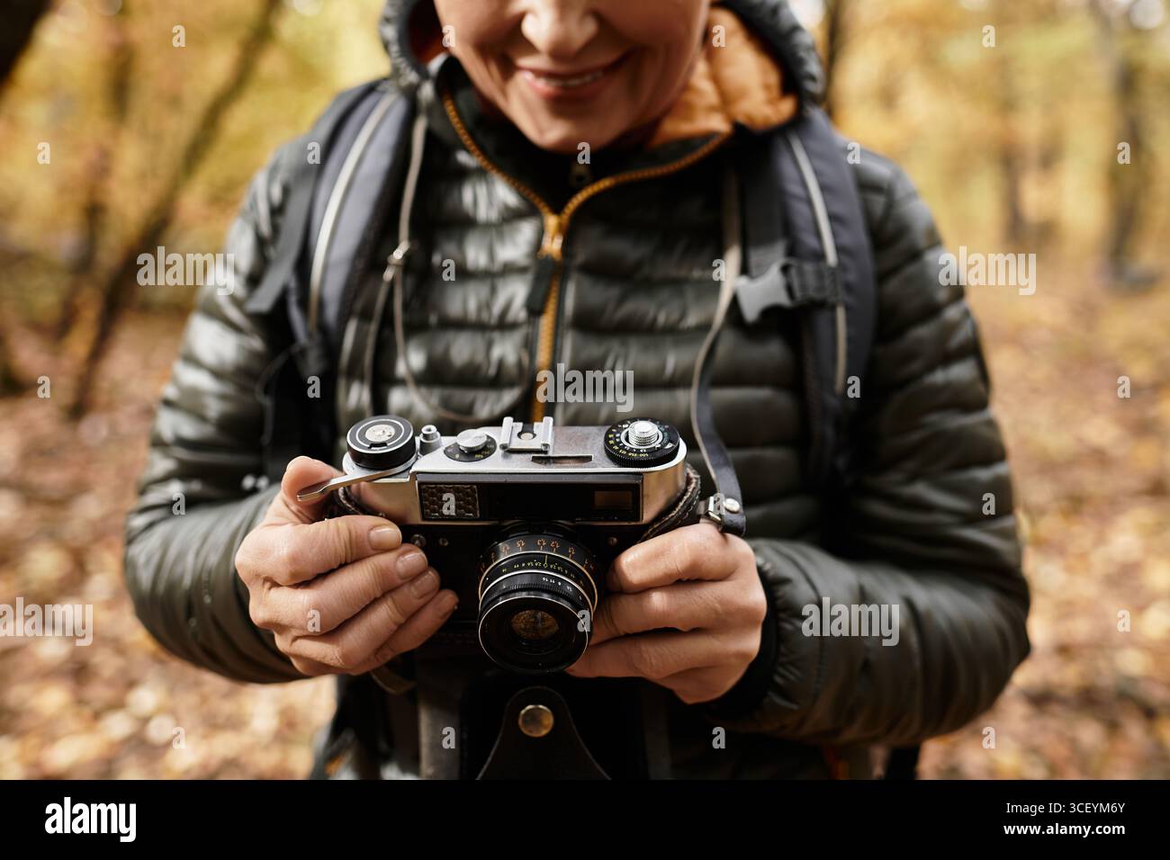 Eine ältere Frau genießt die Natur, während sie Fotos in einer bunten Waldlandschaft macht Stockfoto