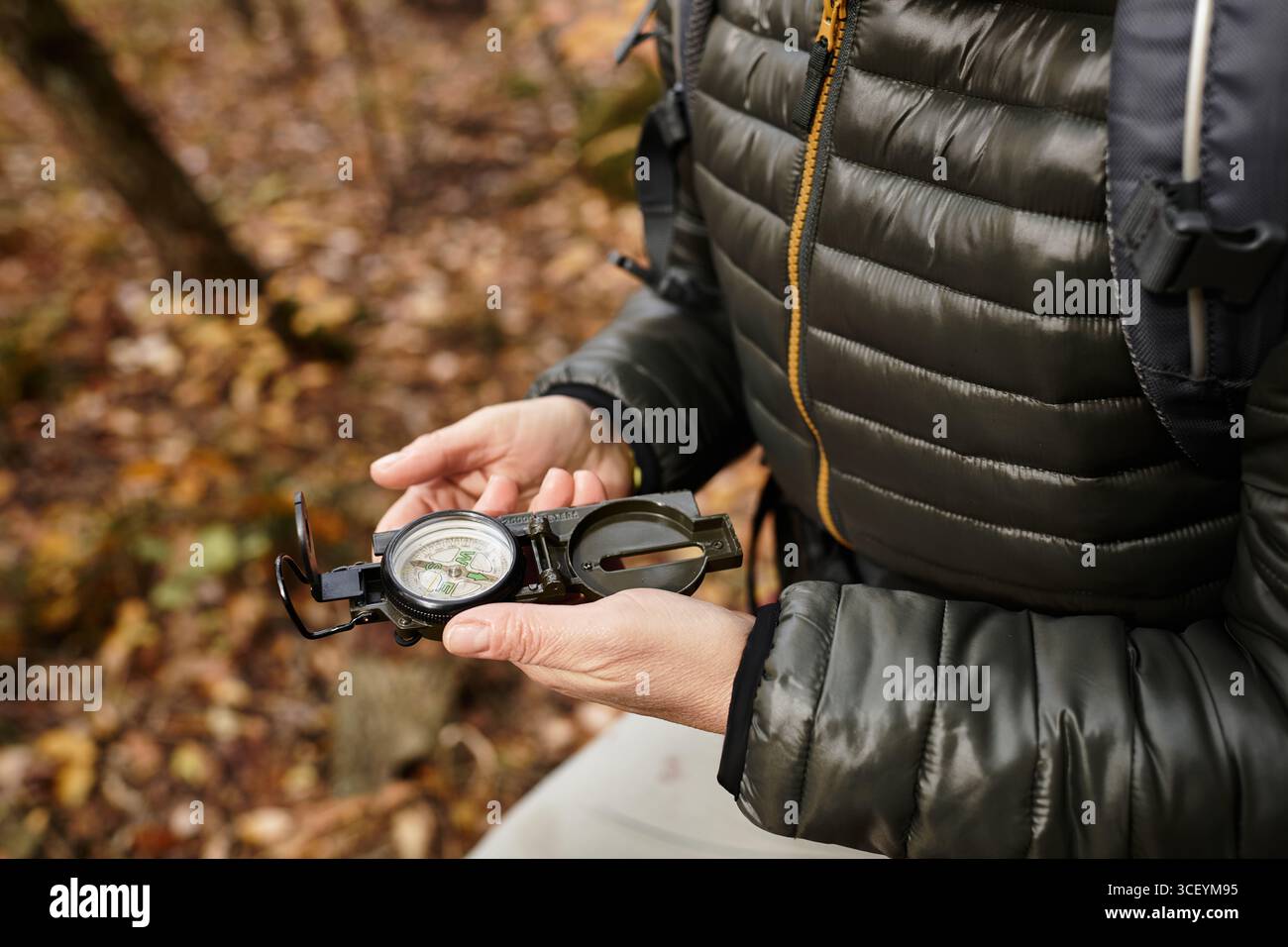Eine ältere Frau genießt die Natur, während sie mit einem Kompass ihr Wanderabenteuer im Wald leitet. Stockfoto