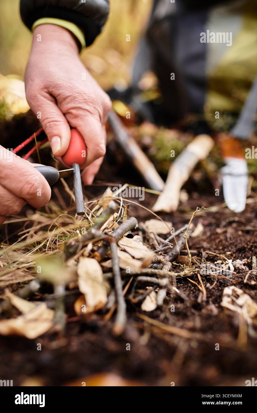 Eine Seniorin bereitet sich geschickt auf das Anzünden in einem ruhigen Wald vor und genießt die Freude am Wandern. Stockfoto