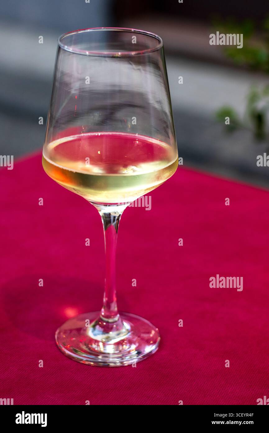 Ein Glas Weißwein auf einem roten Tisch Stockfoto