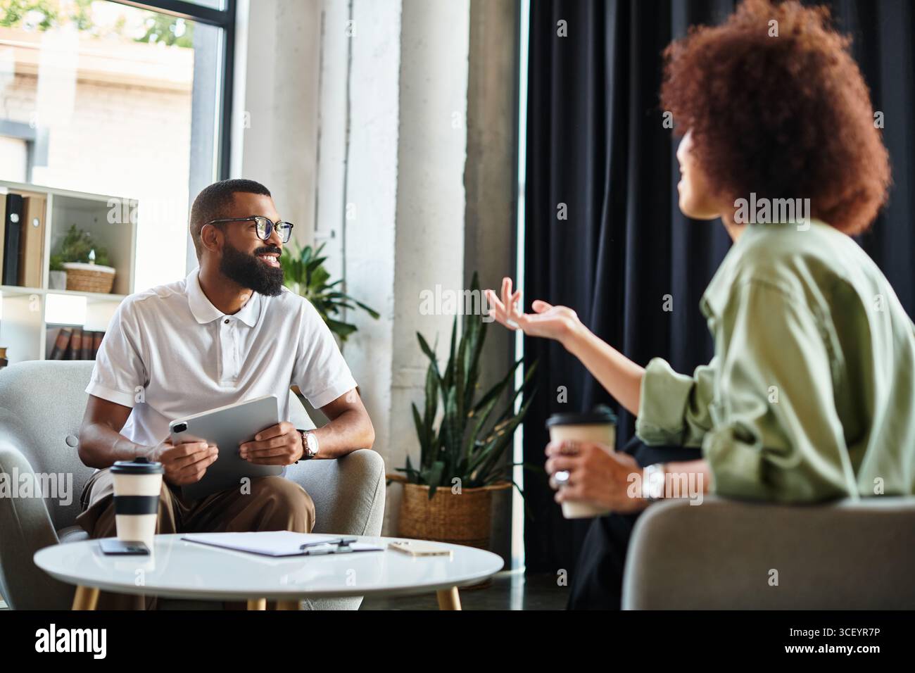 Ein junger Mann und eine junge Frau führen ein Interview in einem stilvollen Studio-Umfeld. Stockfoto