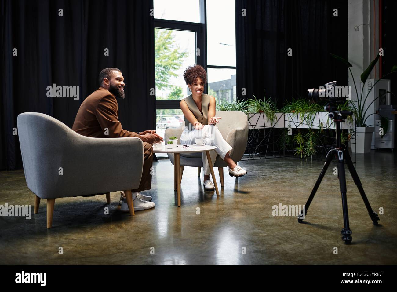 Zwei junge Profis verbinden sich während eines Vorstellungsgesprächs selbstbewusst in einem hellen Studio. Stockfoto