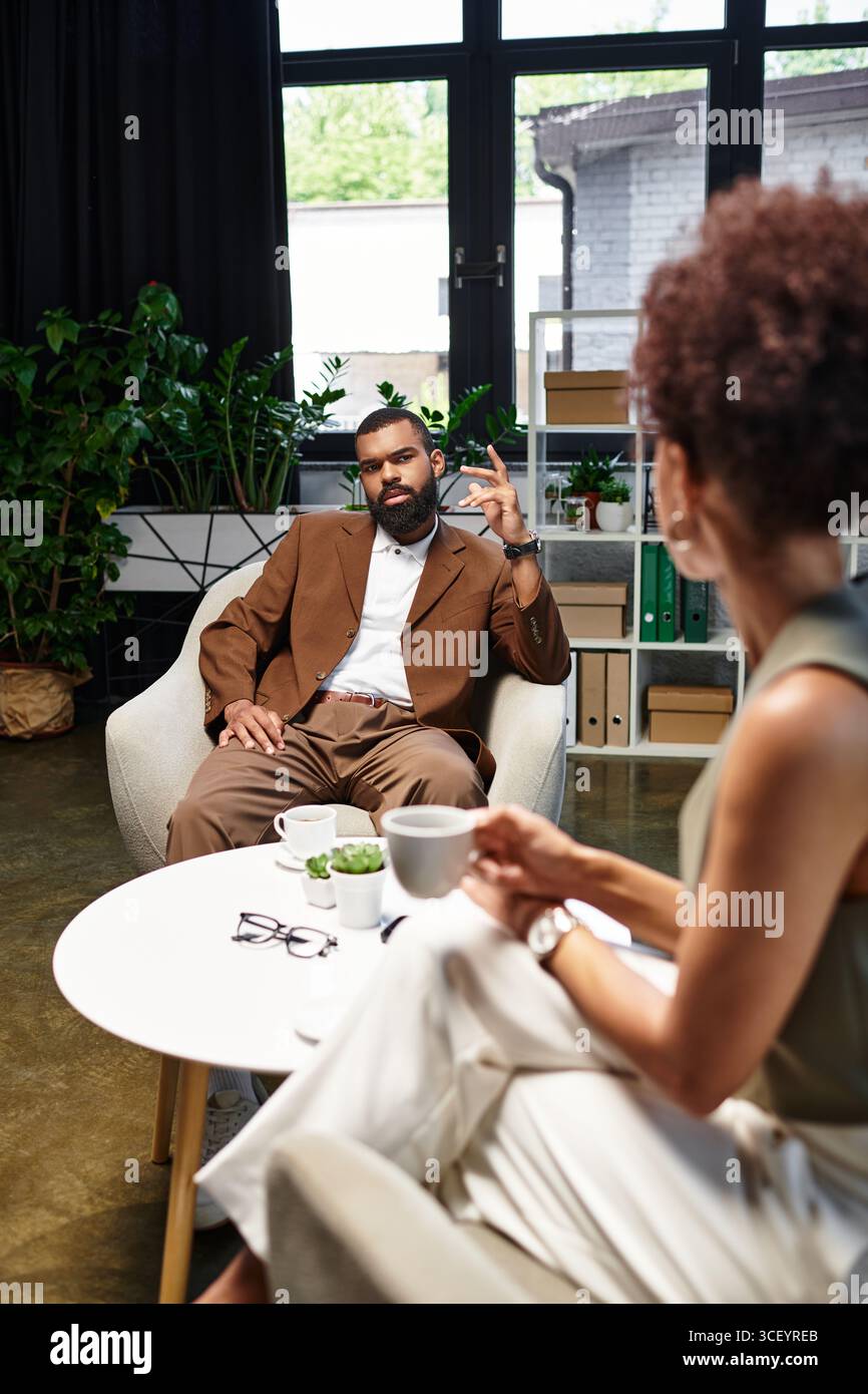 Ein junger Mann und eine junge Frau führen ein Interview in einem stilvollen Studio voller Grün. Stockfoto