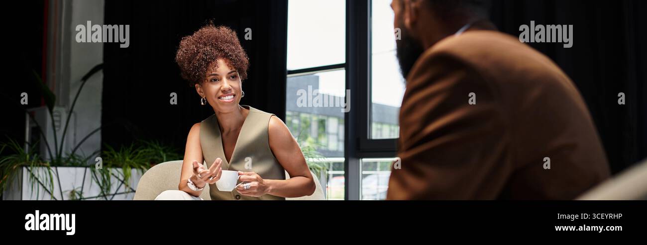 Eine fröhliche Frau diskutiert ihre Qualifikationen mit einem potenziellen Gastgeber in einem stilvollen Studio. Stockfoto