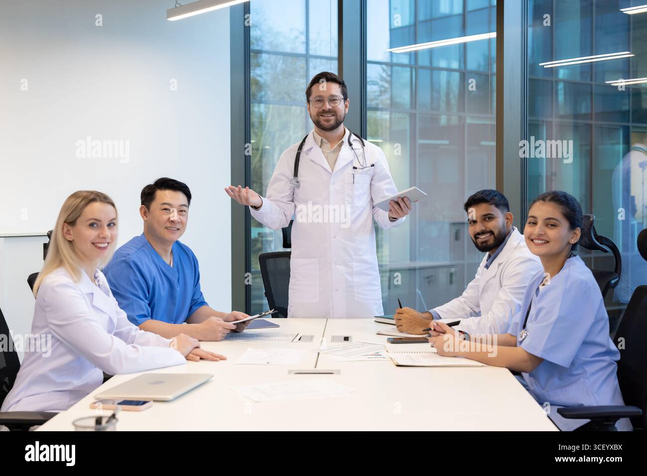 Eine Gruppe verschiedener medizinischer Fachkräfte führt eine gemeinsame Diskussion in einem modernen Büro, gibt Ideen aus und arbeitet an Strategien für die Patientenversorgung und organisatorische Verbesserung zusammen. Stockfoto