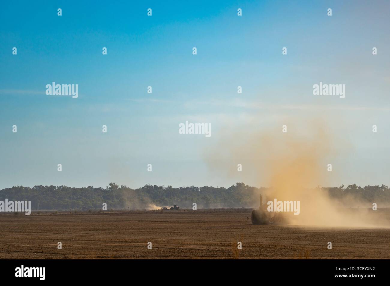Staubwolken steigen hinter einem großen 8-Rad-Traktor in die Luft auf, der Weizenernte in den Ebenen bei Leeton and Griffith, NSW, Aust. Stockfoto
