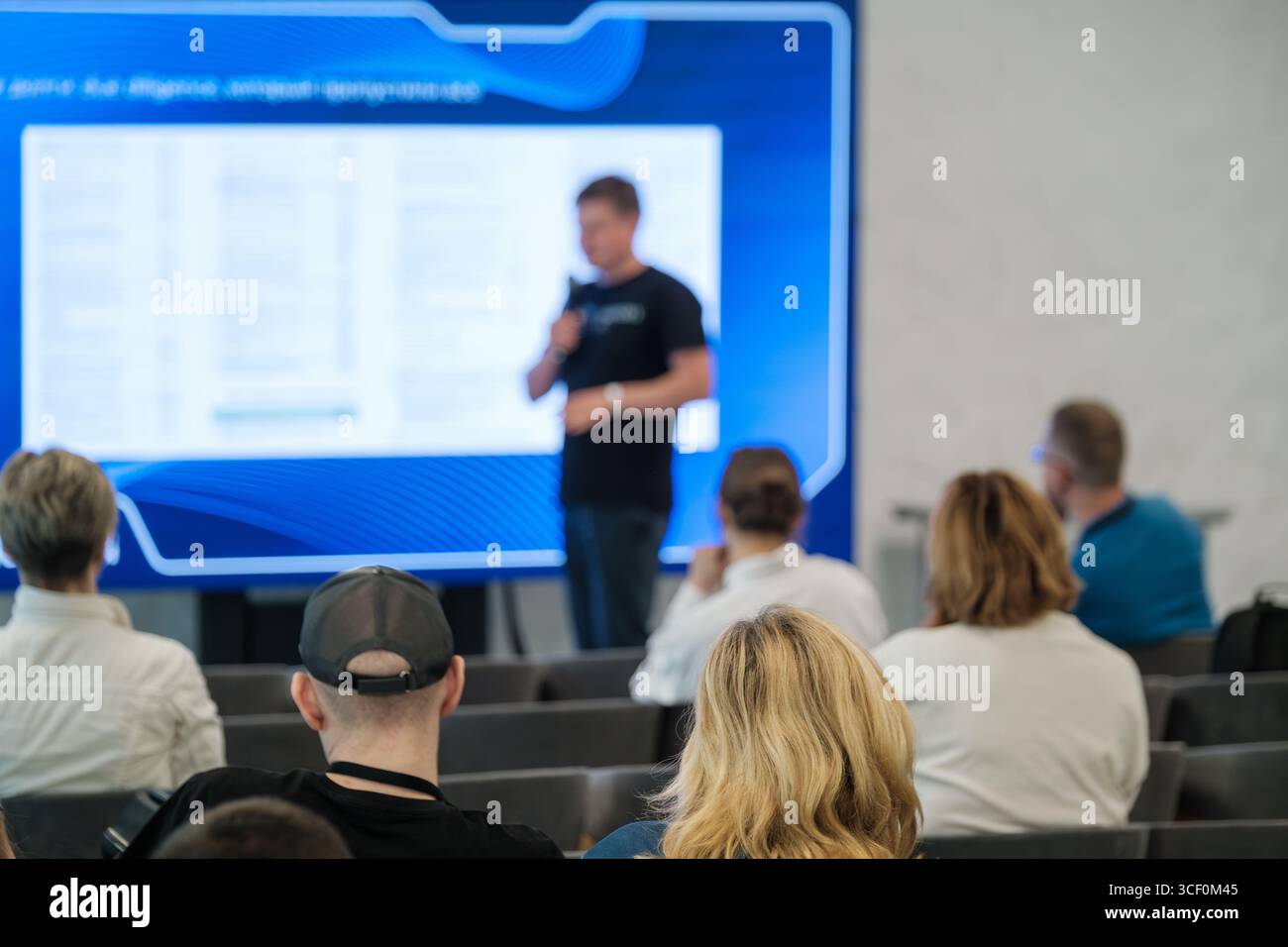 Publikum, das einem Sprecher auf einer Konferenz zuhört, in der eine geschäftliche oder informative Präsentation präsentiert wird. Stockfoto