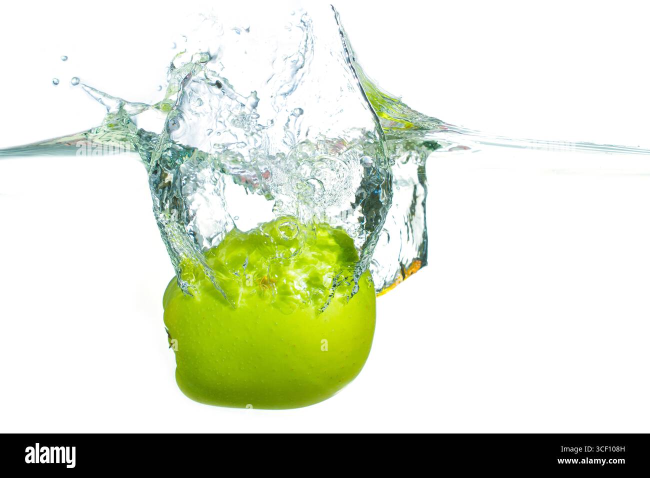 Dynamischer Spritzer Wasser, der durch einen grünen Apfel entsteht, der in klare Flüssigkeit fällt und mit der Zeit gefroren ist, wodurch die lebendige Farbe und Bewegung der Frucht hervorgehoben wird. Stockfoto