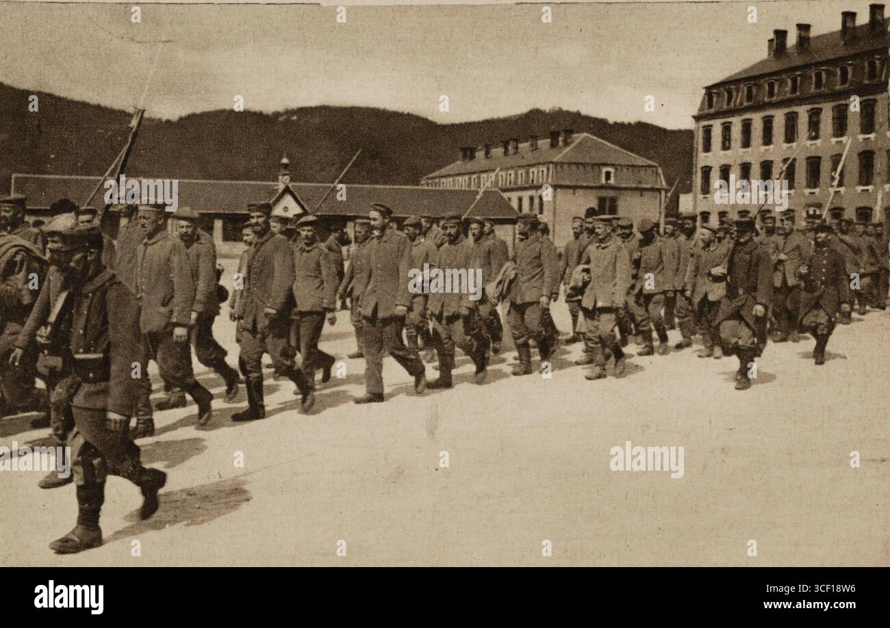 Eine Propagandakarte aus dem Ersten Weltkrieg, die deutsche Kriegsgefangene zeigt, die von französischen Truppen gefangen genommen wurden, während sie zwischen 1914 und 1918 durch ein Dorf in Lothringen marschierten. Stockfoto
