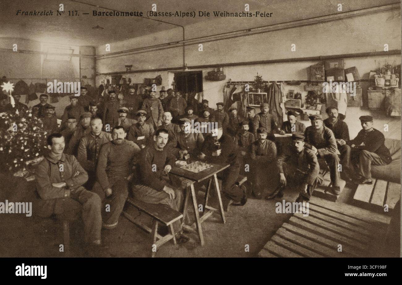 Eine Propagandakarte aus dem Ersten Weltkrieg, die eine große Gruppe deutscher Gefangener zeigt, die Weihnachten im Lager Barcelonnette in Frankreich feiert. Auf dem Foto posieren sie für ein Foto, spielen Schach und sitzen an einem Weihnachtsbaum. Datum unbekannt (1914-1918). Stockfoto