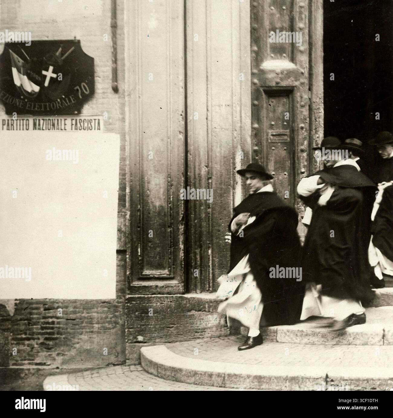 Nach dem Lateranvertrag 1929 entwickelten Benito Mussolinis faschistisches Regime und die katholische Kirche eine engere Beziehung. Dieses Foto zeigt dominikanische Priester, die ein faschistisches Hauptquartier in Rom verlassen, was die Allianz zwischen Faschisten und Geistlichen widerspiegelt. Stockfoto