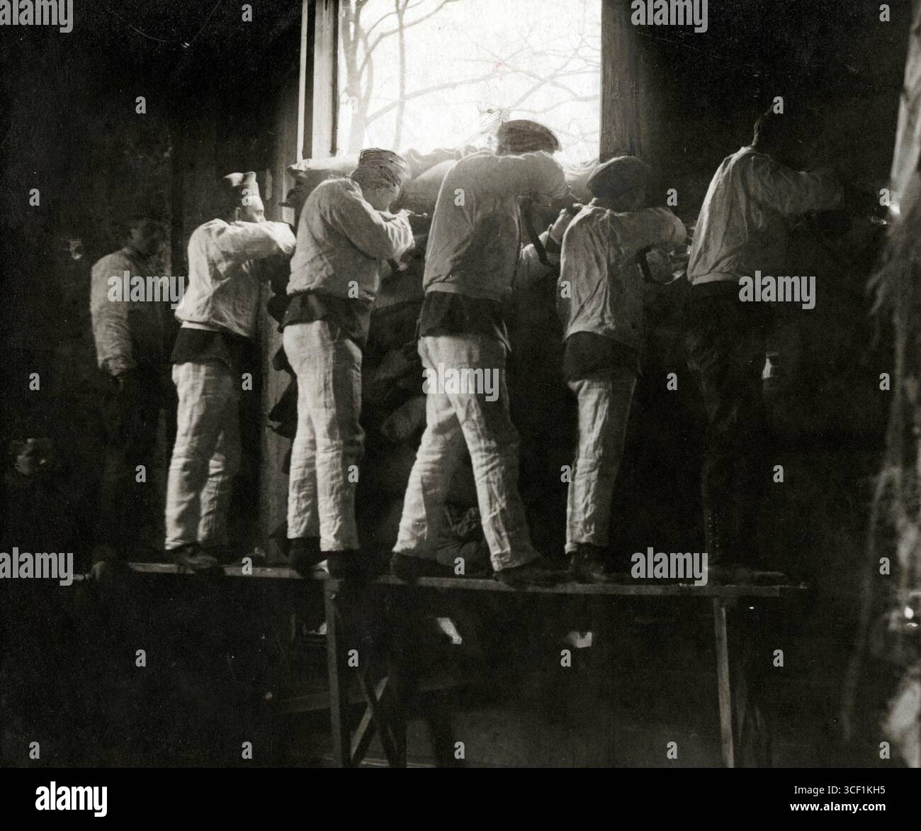 Niederländische Soldaten werden während einer Trainingsübung im Jahr 1915 durch Löcher in einem Haus geschossen. Dieses Bild zeigt militärische Taktiken und Kampfvorbereitungen während des Ersten Weltkriegs. Stockfoto