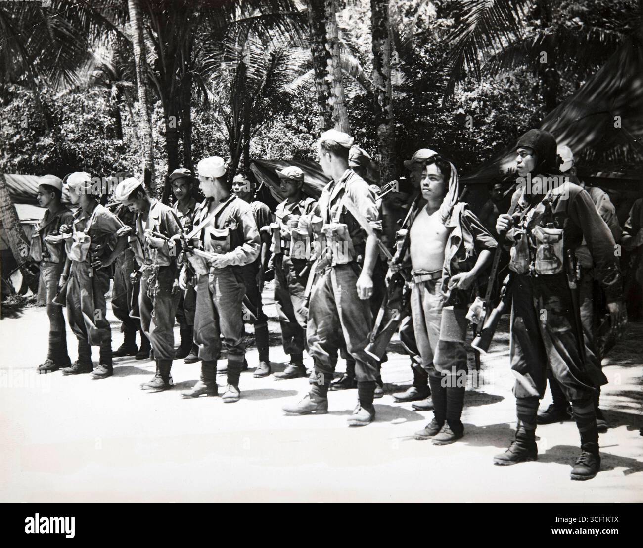 Ein Foto aus den 1940er-1950er Jahren, das Mitglieder der N.E.I. Armee auf Biak Island während des aktiven Dienstes nach dem Training in Australien zeigt. Die Soldaten werden in einem Dschungel dargestellt, was ihre Patrouillenaufgaben hervorhebt. Stockfoto