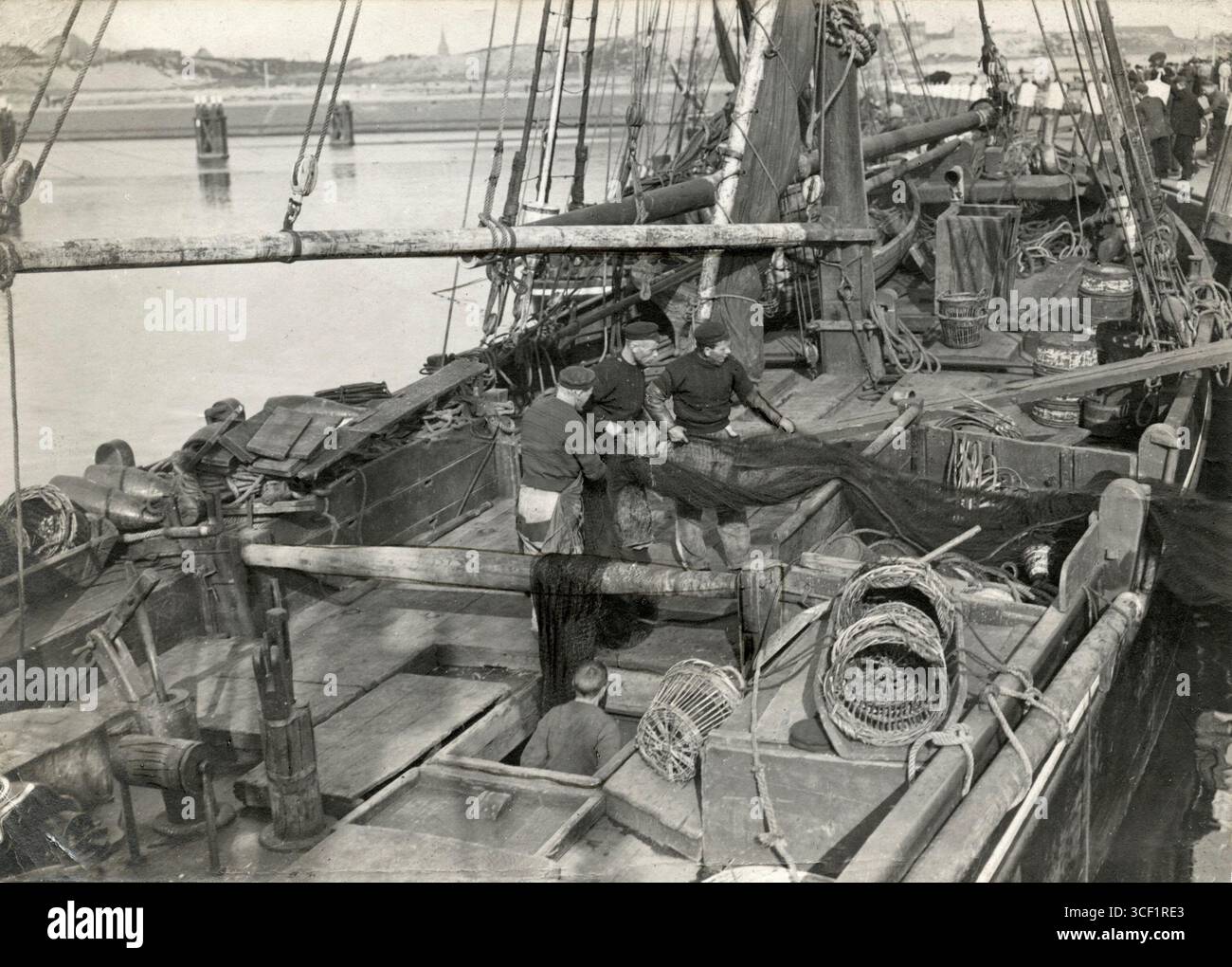 Reinigung und Einstieg von Netzen auf einem Fischerboot in Scheveningen, Niederlande, im Jahr 1913. Diese Szene fängt das tägliche Leben in der Fischereiindustrie während des frühen 20. Jahrhunderts ein. Stockfoto