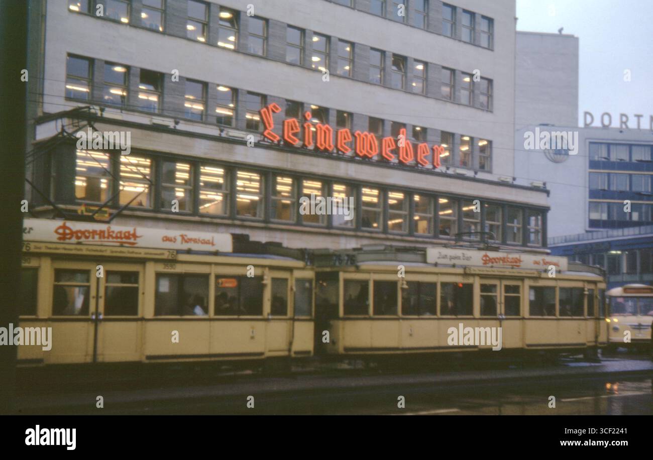 Straßenbahnen Kaufhaus Leineweber und Dortmund, April 1963. Straßenblick mit Neonschildern und öffentlichen Verkehrsmitteln in der Nachkriegsdeutschland. Stockfoto