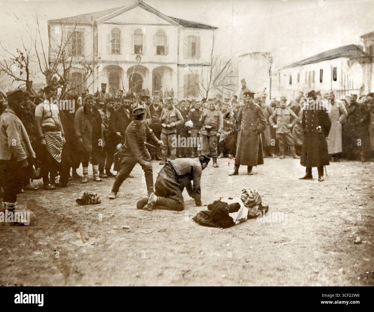 Soldaten, die während des Ersten Balkankrieges im Dezember 1912 geplündert wurden, werden auf einem Platz in Pristina bestraft, während andere Soldaten beobachten. Stockfoto