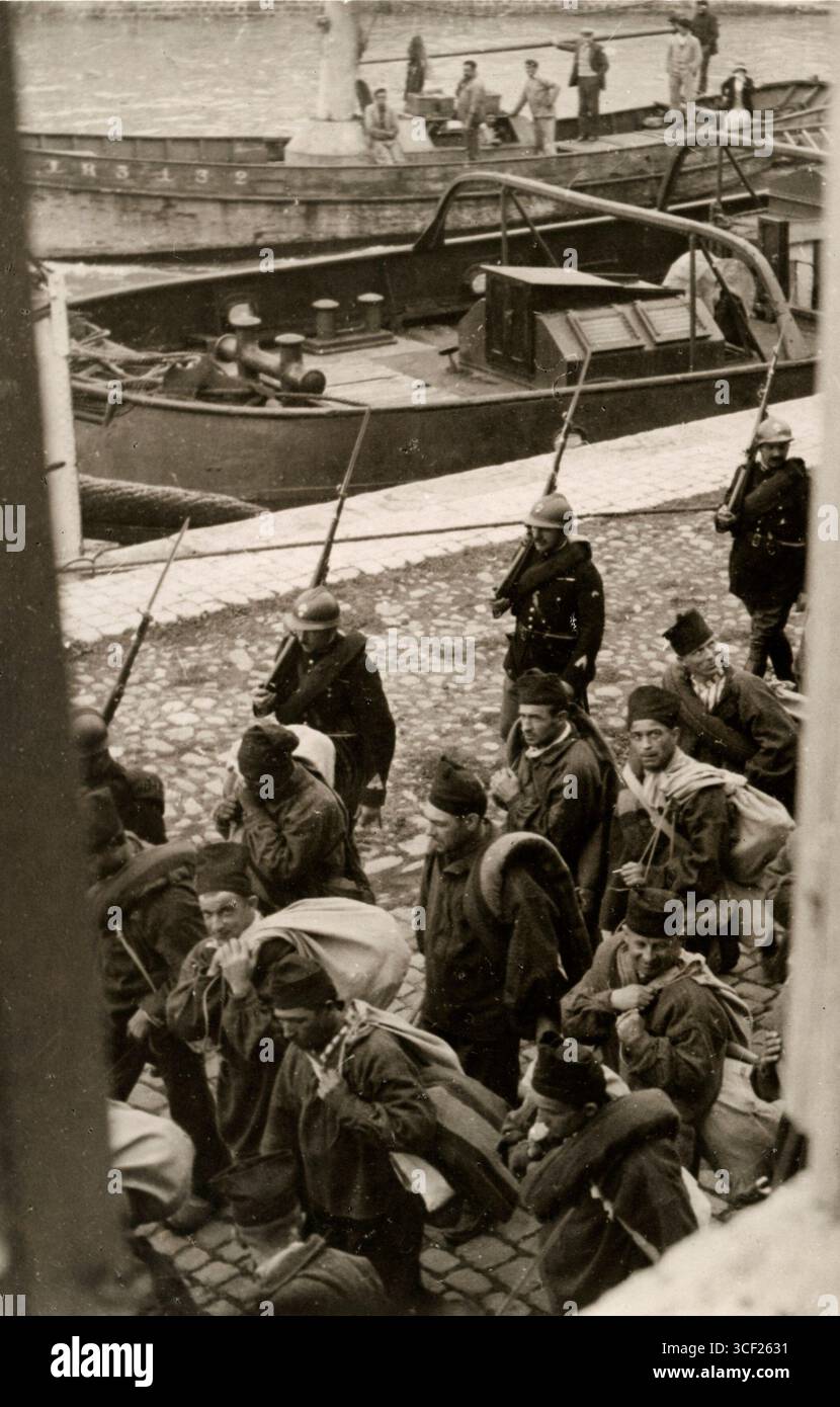 Gefangene laufen unter der Bewachung von Soldaten auf ein Boot zu, das sie 1935 in die französische Strafkolonie Devil's Island transportieren wird. Stockfoto