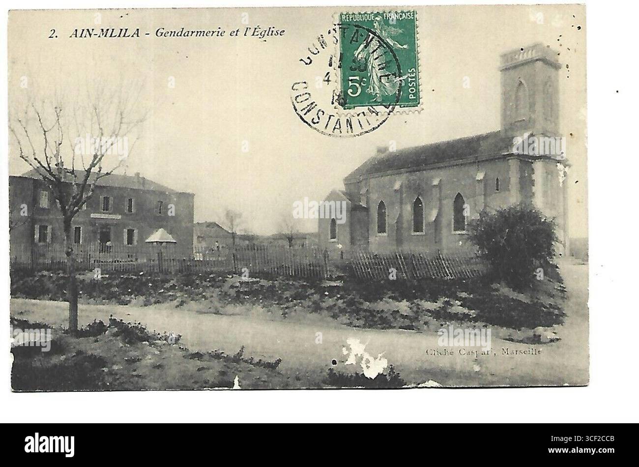 Ein Foto aus den 1900er Jahren, das sowohl die Gendarmerie als auch die Kirche in Ain-Mlila, einer Stadt in Algerien, zeigt. Diese Gebäude sind wichtige Merkmale der Architektur der Stadt. Stockfoto
