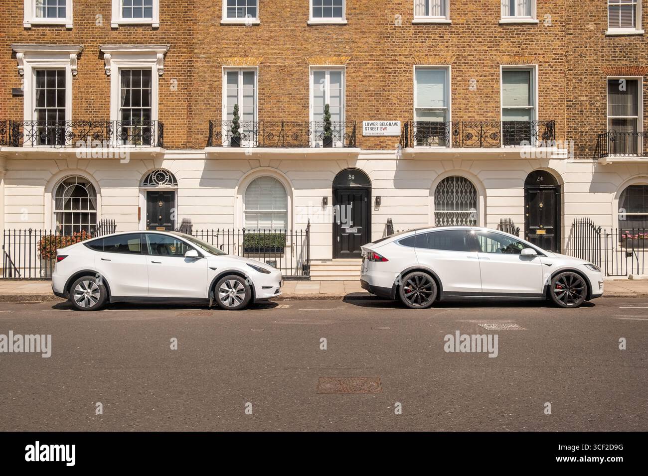 LONDON – 6. AUGUST 2025: Weiße Tesla-Elektrofahrzeuge parken auf der eleganten Wohnstraße im Zentrum von London Stockfoto