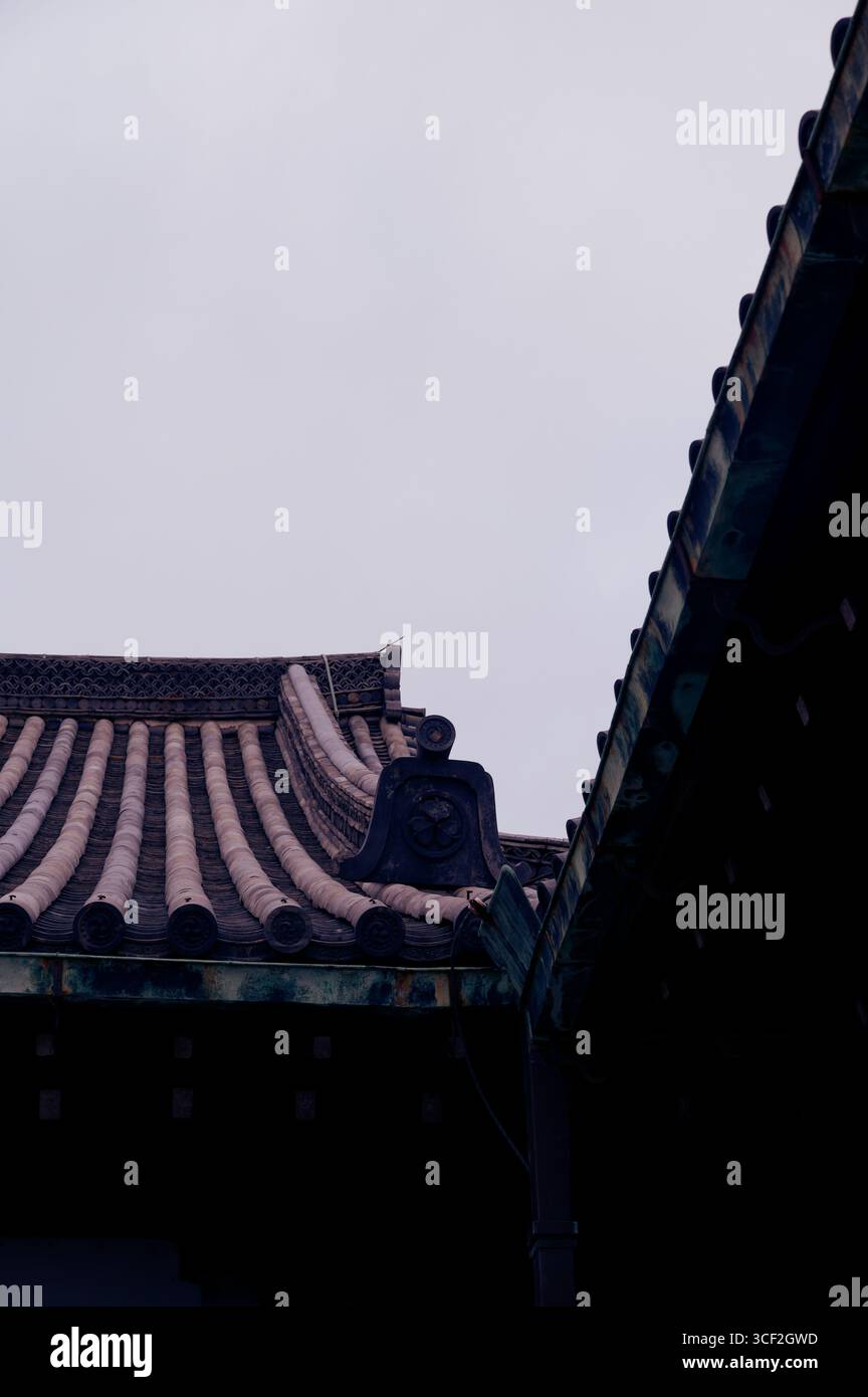 Traditionelle gekachelte Dächer des Schlosses Nijo in Kyoto heben sich von einem grauen Winterhimmel ab Stockfoto