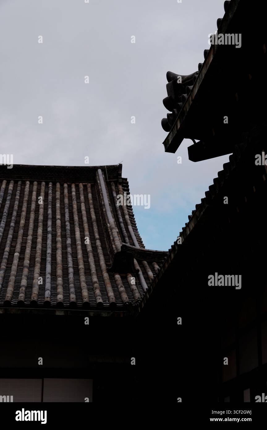 Traditionelle Ziegeldächer des Schlosses Nijo in Kyoto heben sich von einem Winterhimmel ab Stockfoto