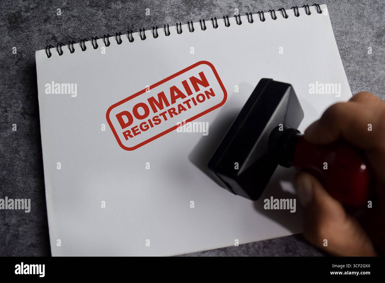 Roter Griff Gummistempel und Domäne Registrierungstext über dem Buch isoliert auf hölzernem Hintergrund Stockfoto