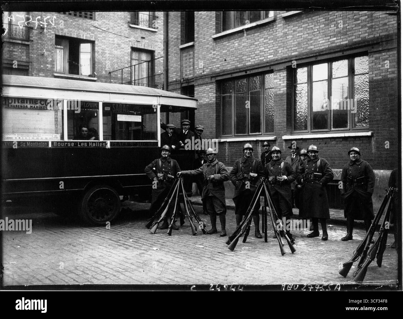 Dieses Pressefoto vom November 1925 zeigt Busse, die von einer unklaren Straße abfahren, wobei Truppen während der Veranstaltung die Sicherheit übernehmen. Er hebt die historische Rolle der Streitkräfte für die städtische Sicherheit hervor. Stockfoto