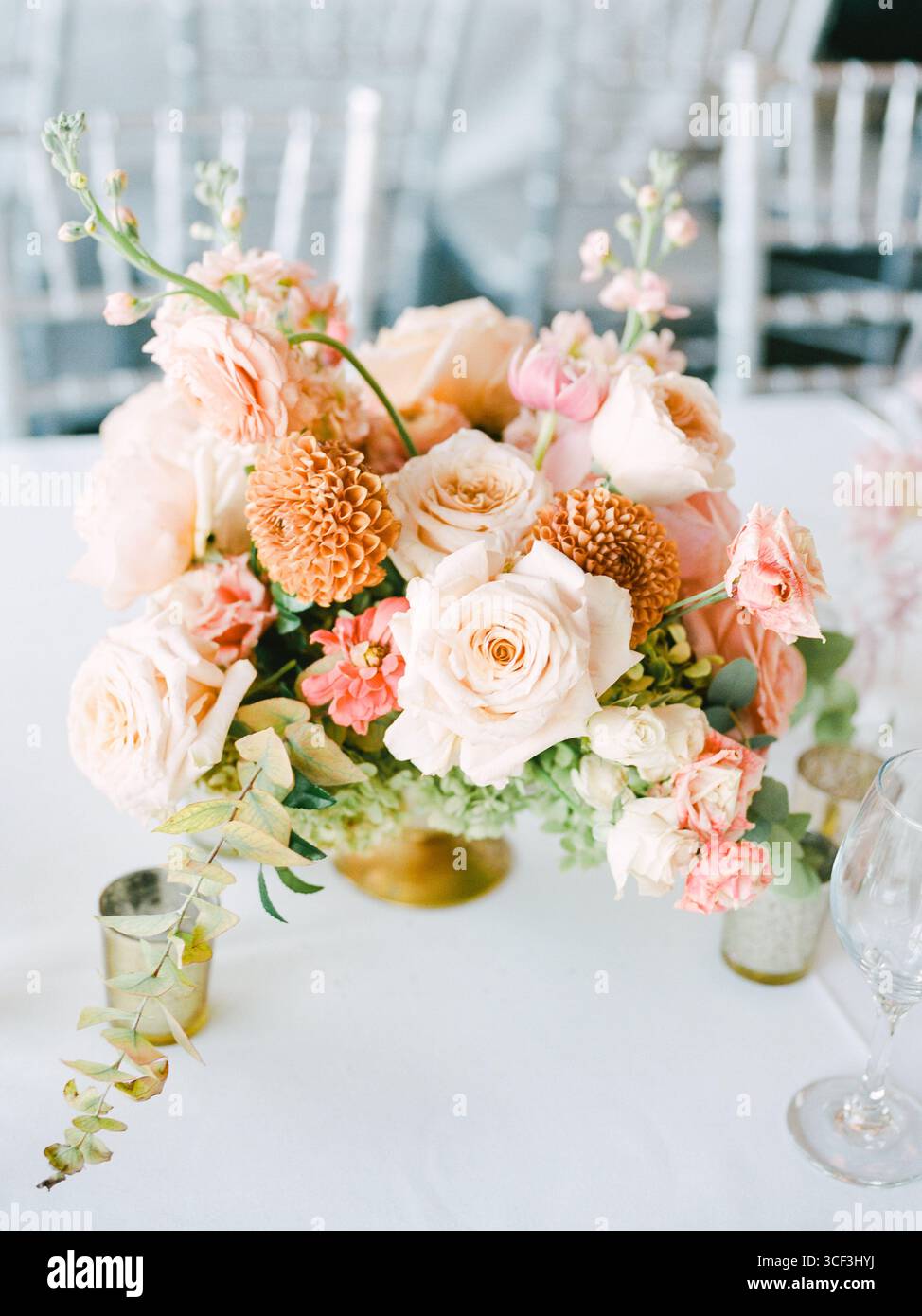 Ein wunderschönes Blumenmotiv zeigt eine Auswahl an zarten Rosen und einzigartigen Blüten, die den stilvollen Tisch unterstreichen. Stockfoto