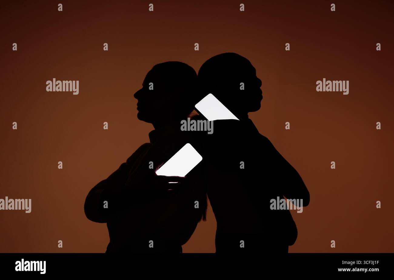 Silhouetten von zwei Personen, die Smartphones hintereinander halten, mit leuchtenden leeren Bildschirmen auf dunklem Hintergrund, ideal für mobile Mockups, soziale Medien, und Stockfoto