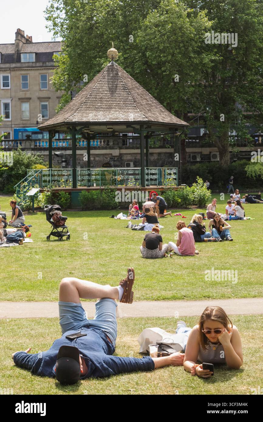 England, Somerset, Bath, Parade Gardens, Paare entspannen auf Grass Stockfoto